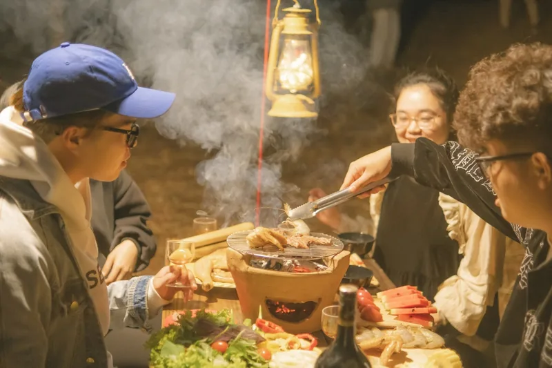 Nhóm bạn quây quần bên bếp than nghi ngút khói trong bữa tối cắm trại về đêm gần Đà Lạt.