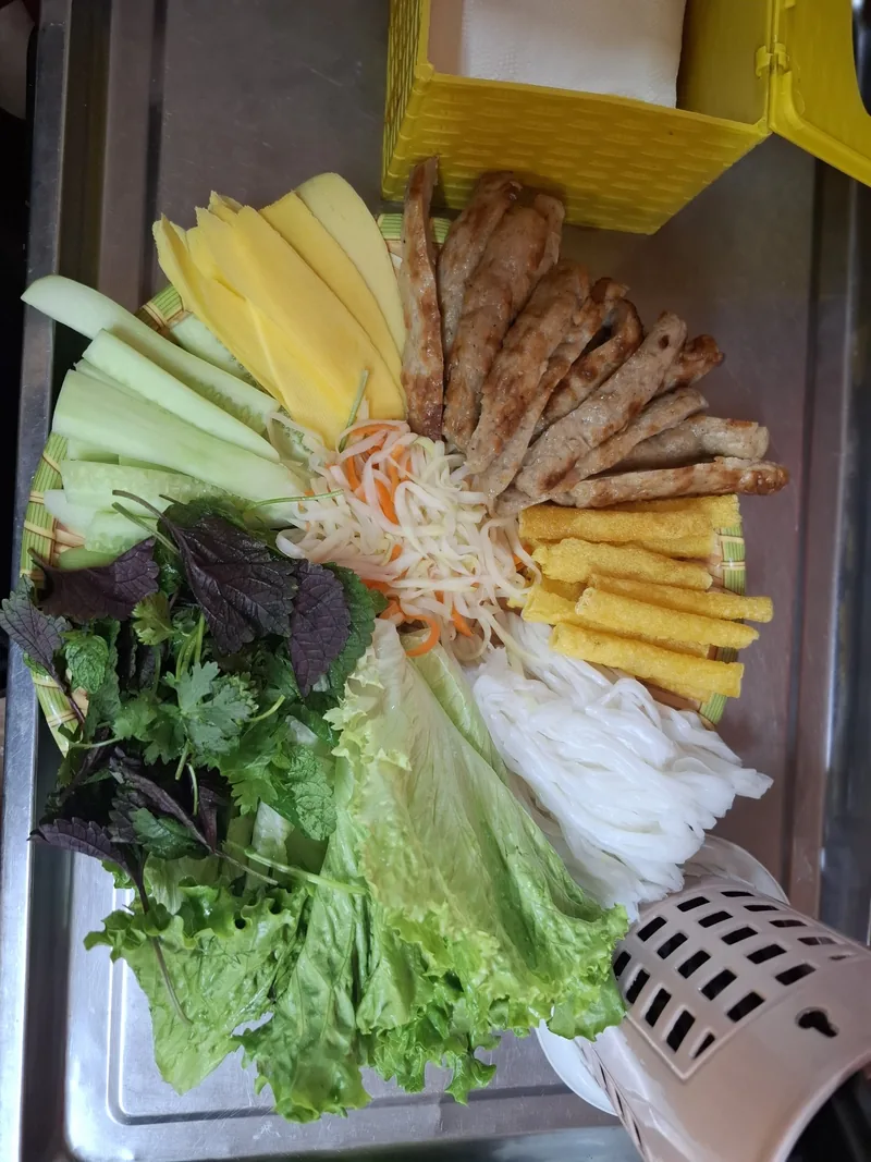 Đĩa chả nướng, bún, nem chiên và rau thơm được bày biện cho bữa ăn ở Hà Nội.