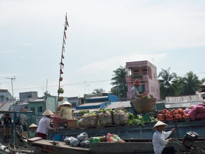 Người bán hàng đội nón lá bày bán rau củ và trái cây trên thuyền tại chợ nổi Cái Răng, Cần Thơ.